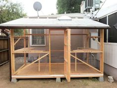 a chicken coop in the back yard next to a building with a satellite dish on top