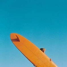 a man standing on top of a yellow surfboard in the air with his arms out