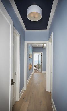 an empty hallway with blue walls and white trim on the ceiling is seen in this image