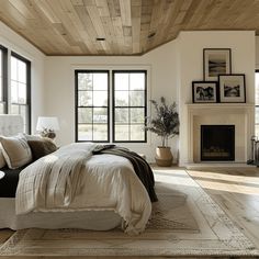 a large bed sitting in a bedroom next to two windows and a fireplace on top of a hard wood floor