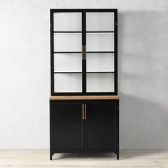 a black cabinet with glass doors and wooden top sitting in front of a white wall