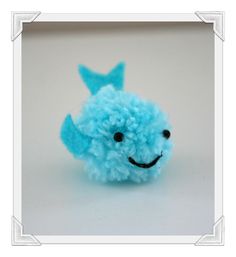 a blue stuffed animal with a smile on it's face and eyes, sitting in front of a white background