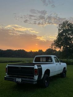 a pickup truck parked in the grass at sunset