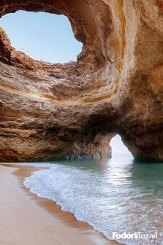 the water is blue and green as it flows under an arch shaped rock formation at the beach