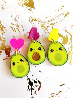 three avocado shaped earrings with hearts hanging from them on a white surface,