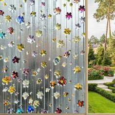 a glass window with flowers on it in the middle of a garden and an outside view