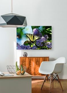 a white chair sitting in front of a painting on the wall next to a table