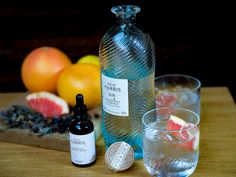 a bottle of water next to two glasses and some fruit on a cutting board with an empty bottle