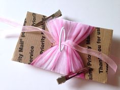 a pink ribbon wrapped in brown paper with a pair of scissors on top of it