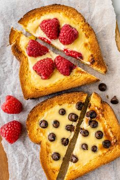 two pieces of bread with cheese and raspberries on top, one slice has been cut in half