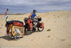 two people riding on the back of a bike with luggage strapped to it's side