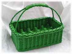 a green wicker basket with bottles in it on a white cloth covered tablecloth