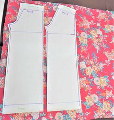 two pieces of paper sitting on top of a pink flowered table cloth next to each other