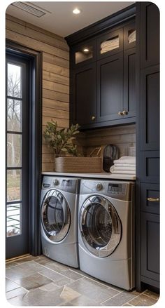 a washer and dryer in a room with wooden walls, black cabinets, and tile flooring