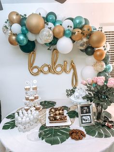 a table topped with lots of desserts and balloons in the shape of baby's name