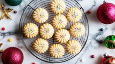 some cookies are sitting on a wire rack next to christmas ornaments and baubles