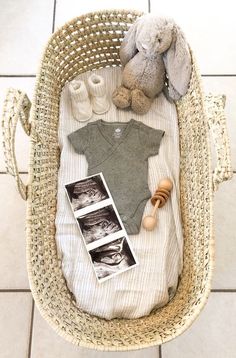 a baby's outfit and teddy bear in a wicker basket on the floor