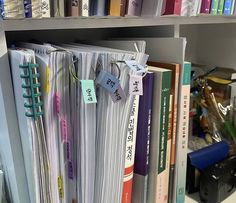 a book shelf filled with lots of books and binders on top of each other