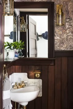 a white sink sitting under a mirror next to a wall mounted faucet in a bathroom