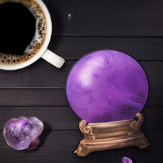 a purple object sitting next to a cup of coffee on top of a wooden table