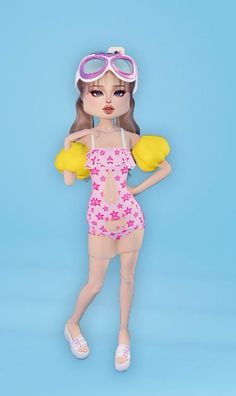 a doll with goggles and swimsuit holding a yellow object in front of a blue background