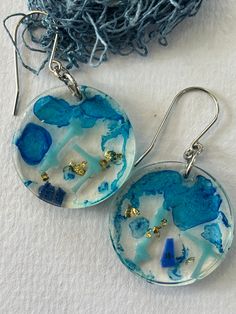 These lightweight earrings have been made with pieces of beach plastic, flakes of gold leaf and translucent blue dye.  This has all been set in a plant based resin [ 77% bio based] to keep it all as environmentally friendly as possible. I have used stainless steel findings.  The resin and beach plastic feature measures 3 cm in diameter. Cadmium-free Blue Earrings As Gift, Unique Blue Hypoallergenic Earrings, Unique Blue Earrings For Beach, Blue Dangle Earrings Cadmium-free, Ocean-inspired Blue Earrings With Ear Wire, Resin Dangle Earrings For Beach, Blue Cadmium-free Drop Earrings, Blue Resin Earrings For The Beach, Blue Resin Earrings For Beach