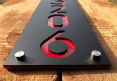 a close up of a metal sign on a wooden surface with the number six in red