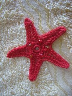 a red crocheted starfish sitting on top of a white blanket