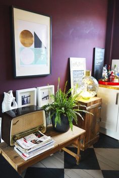 a living room with purple walls and a wooden table topped with a potted plant