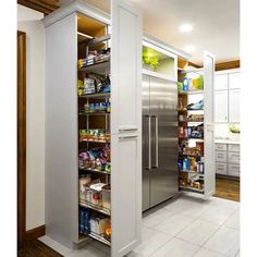 a large pantry in the middle of a kitchen with stainless steel refrigerator and shelves full of food