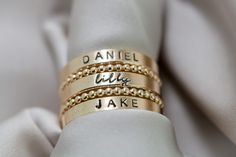 Create your own beautiful set of name rings to show off the people closest to your heart! So simply pretty! Our 3mm high quality 14k Gold-Filled band rings fit one date, name or word in your choice of font. Our rings stack beautifully together, so purchase up to 3 name band rings total for one finger. Please keep the total characters per ring to around 20 max. Up to 3 name ring bands with two spacers will fit on one finger, and we recommend sizing to the next whole size up if you are stacking 3 rings. Please read the sizing details first in the DETAILS section below. D E T A I L S 14k Gold Filled Name Band Rings: Whole US Sizes: 4 - 10 Option to add spacer rings Lowercase tiny script font or UPPERCASE Arial Choose natural or darkened lettering Fit one name, date or word per ring Stamped by Engraved Rings For Women Names, Trendy Rings For Women, Stackable Rings For Each Child, Personalized Stackable 14k Gold Rings, Custom Name 14k Gold Stackable Rings For Anniversary, Custom Name Stackable Rings In 14k Gold For Anniversary, 14k Gold Stackable Rings With Custom Name For Anniversary, Custom Name Stackable 14k Gold Rings For Wedding, Classic Jewelry With Custom Text For Anniversary