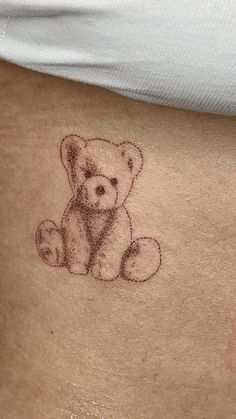 a small teddy bear tattoo on the stomach