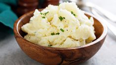 a wooden bowl filled with mashed potatoes on top of a table