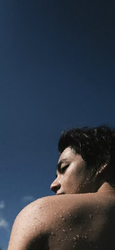 a man with no shirt on standing under a blue sky