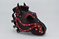 a black and red leather mask with spikes on it's face, in the shape of a horse head