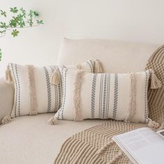 a couch with some pillows on it and a laptop sitting next to the pillow that has tassels