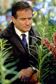 a man in a suit and tie looking at flowers