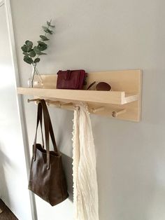 a wooden shelf holding two purses and a handbag hanging from it's hooks