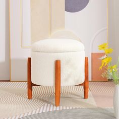 a white ottoman sitting on top of a rug next to a vase filled with flowers