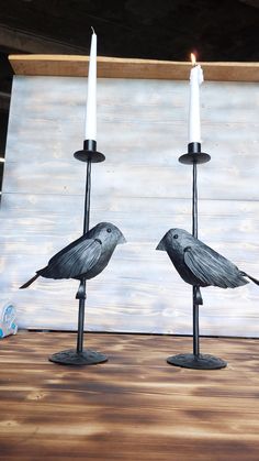 two black candlesticks sitting on top of a wooden table