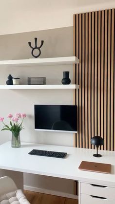 a white desk with a computer monitor, keyboard and mouse on it in front of a striped wall