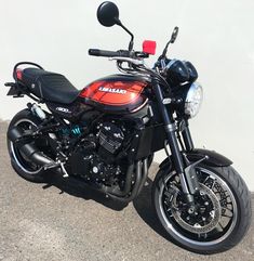 a red and black motorcycle parked next to a white wall