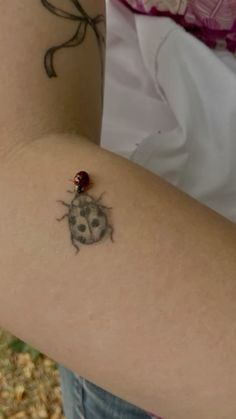 a ladybug tattoo on the back of a woman's arm