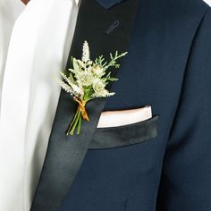 a man wearing a suit and tie with flowers in his lapel flower pin on his lapel