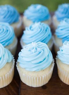 cupcakes with blue frosting sitting on a table