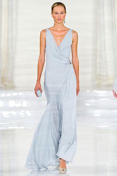 a woman walking down a runway in a blue dress