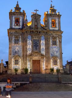 a woman sitting on a bench in front of a church