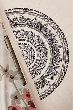 a pen and some paper on top of a flowered table cloth with an intricate design