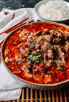 a bowl of meat and vegetable soup with chopsticks on the side