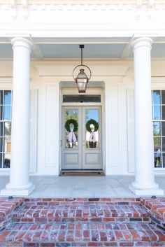 the front door is decorated with wreaths and two white pillars on either side of it